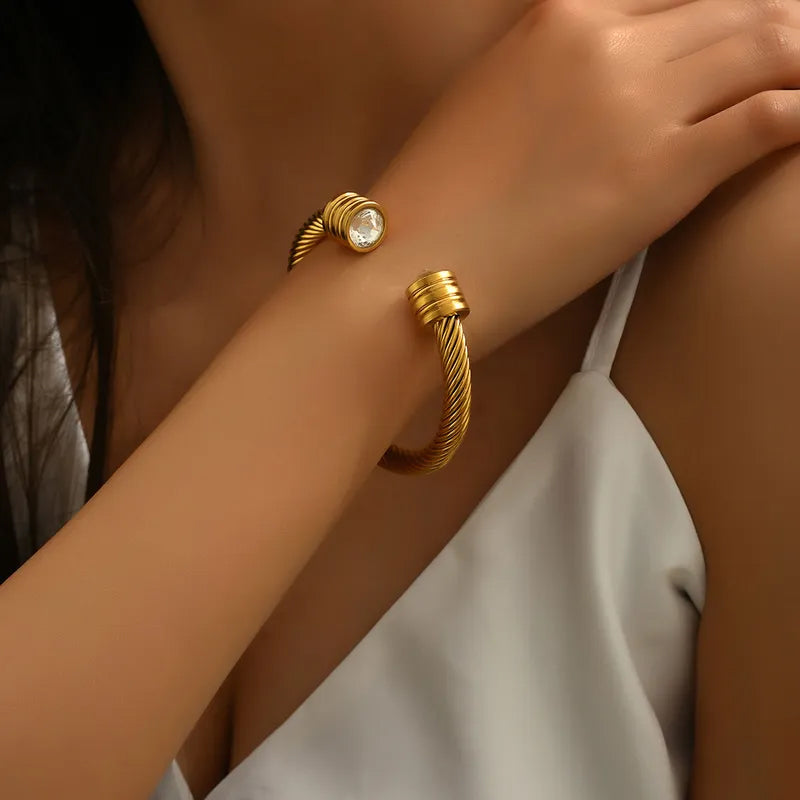 Adora London The Kacie Bangle 18K gold plated twist bangle with rhinestone gem detailing at either end. Chunky style bangle