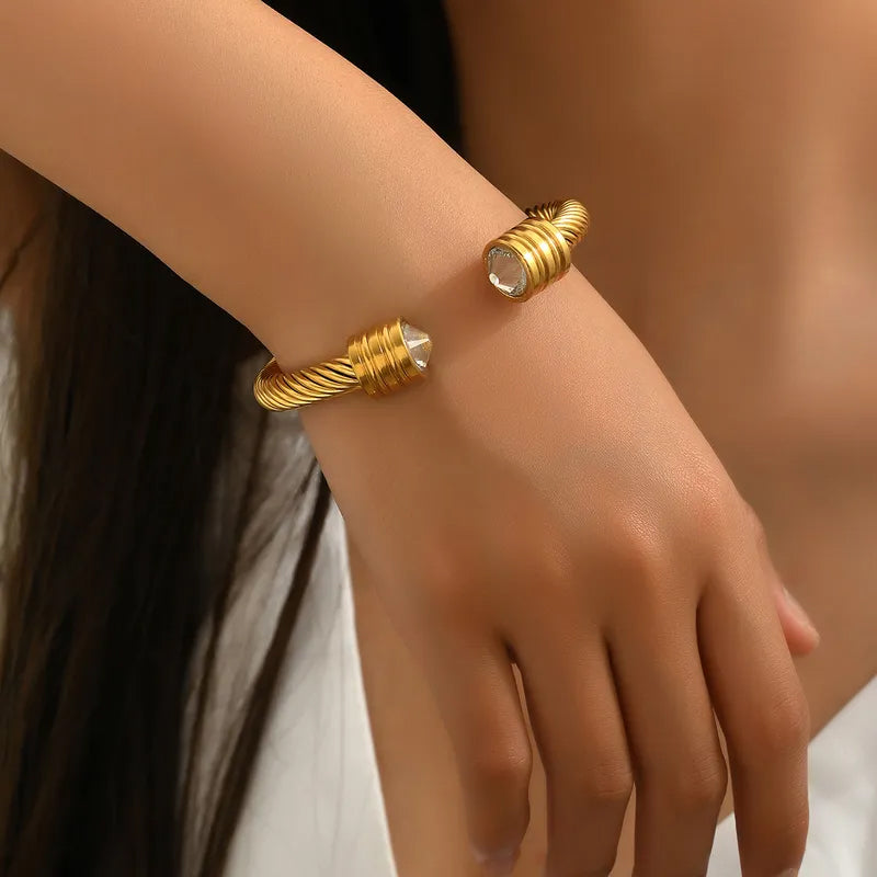 Adora London The Kacie Bangle 18K gold plated twist bangle with rhinestone gem detailing at either end. Chunky style bangle