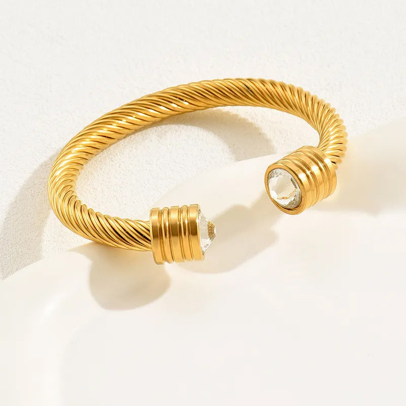 Adora London The Kacie Bangle 18K gold plated twist bangle with rhinestone gem detailing at either end. Chunky style bangle